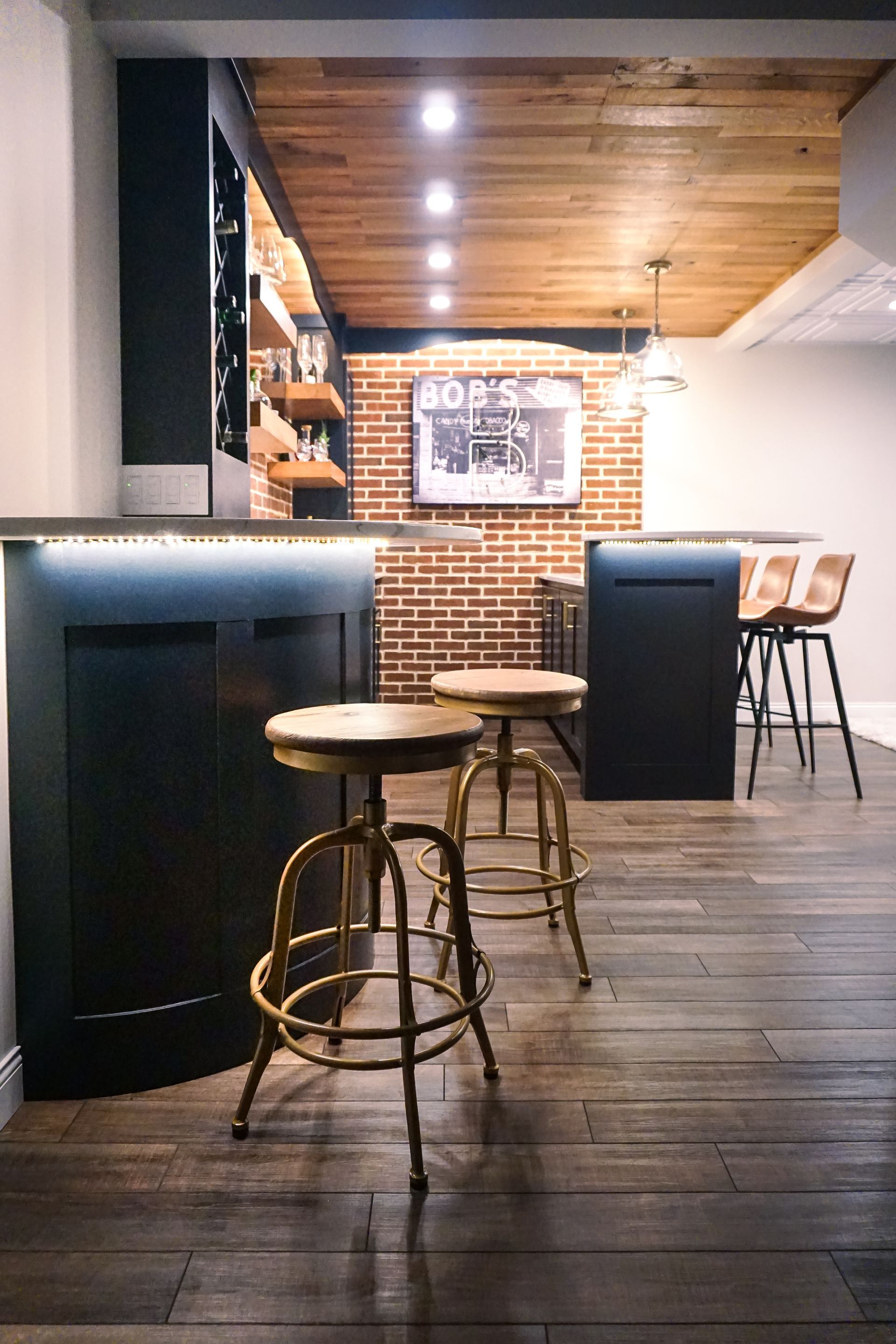Custom black painted, curved wood beverage and bar cabinet with under the counter lighting and stained wood floating shelves.