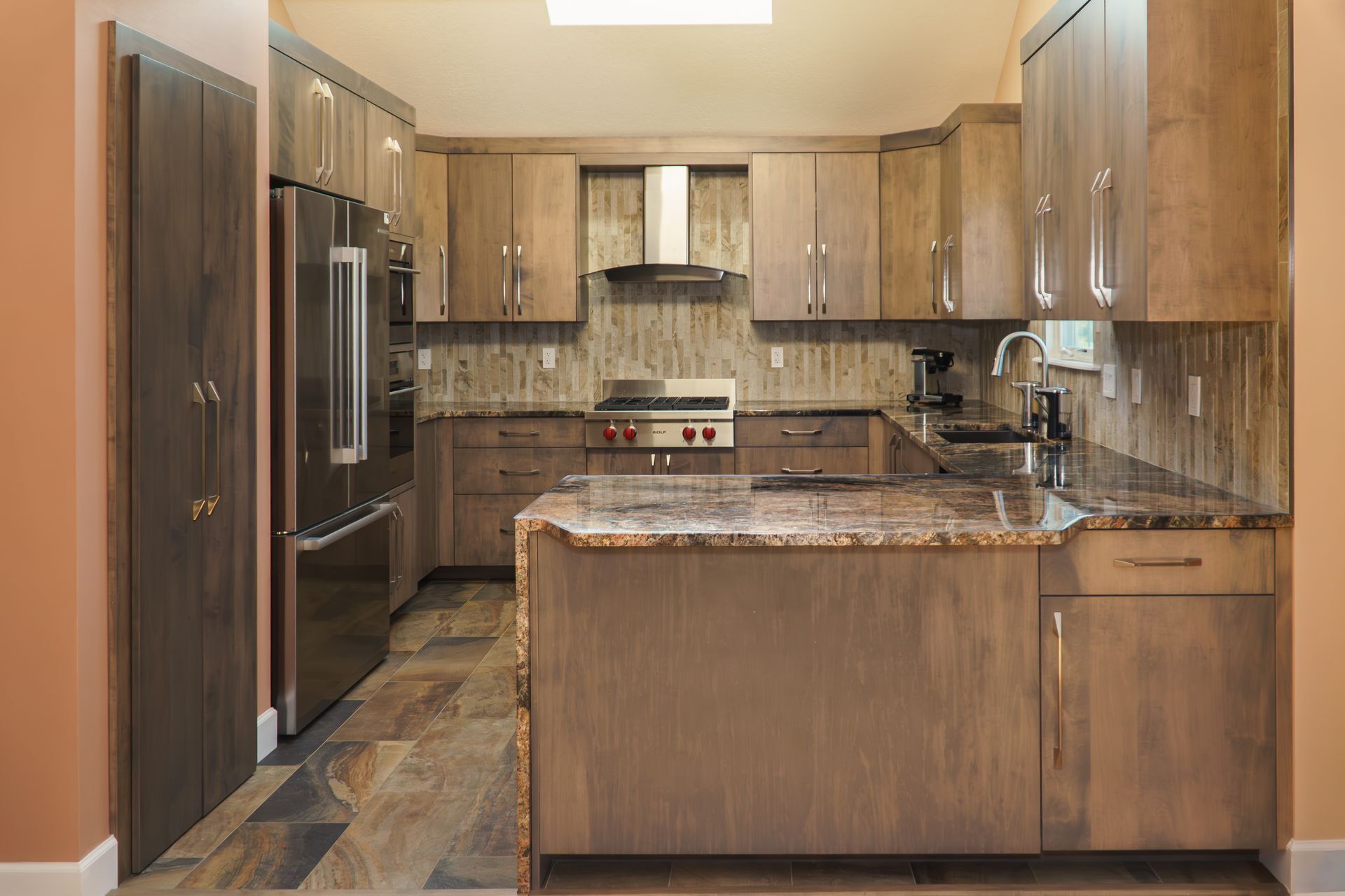 Custom, stained modern frameless wood  kitchen cabinets and island, stainless appliances and range hood.
