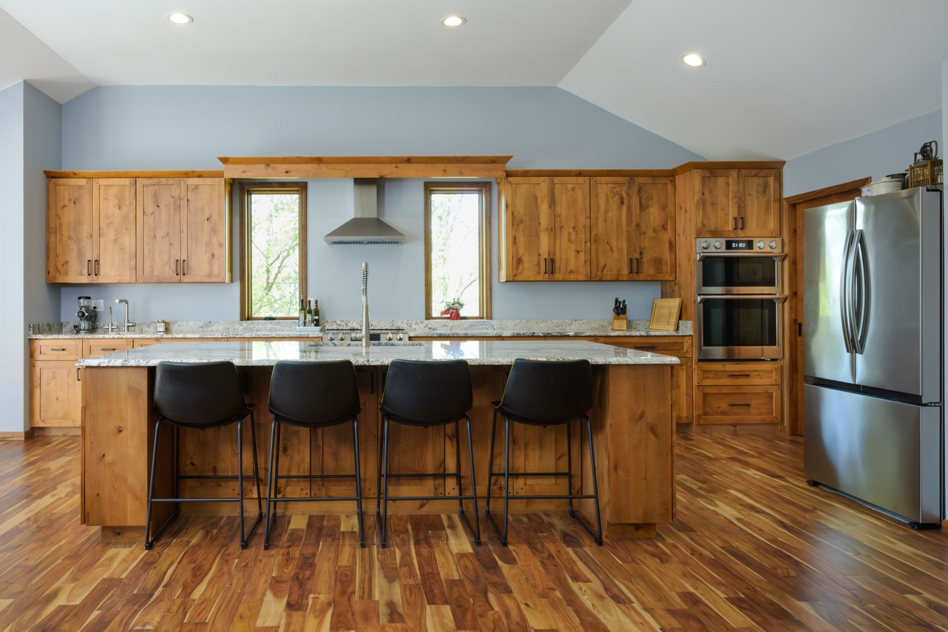 Custom, stained modern wood  kitchen cabinets and island, stainless appliances and range hood.