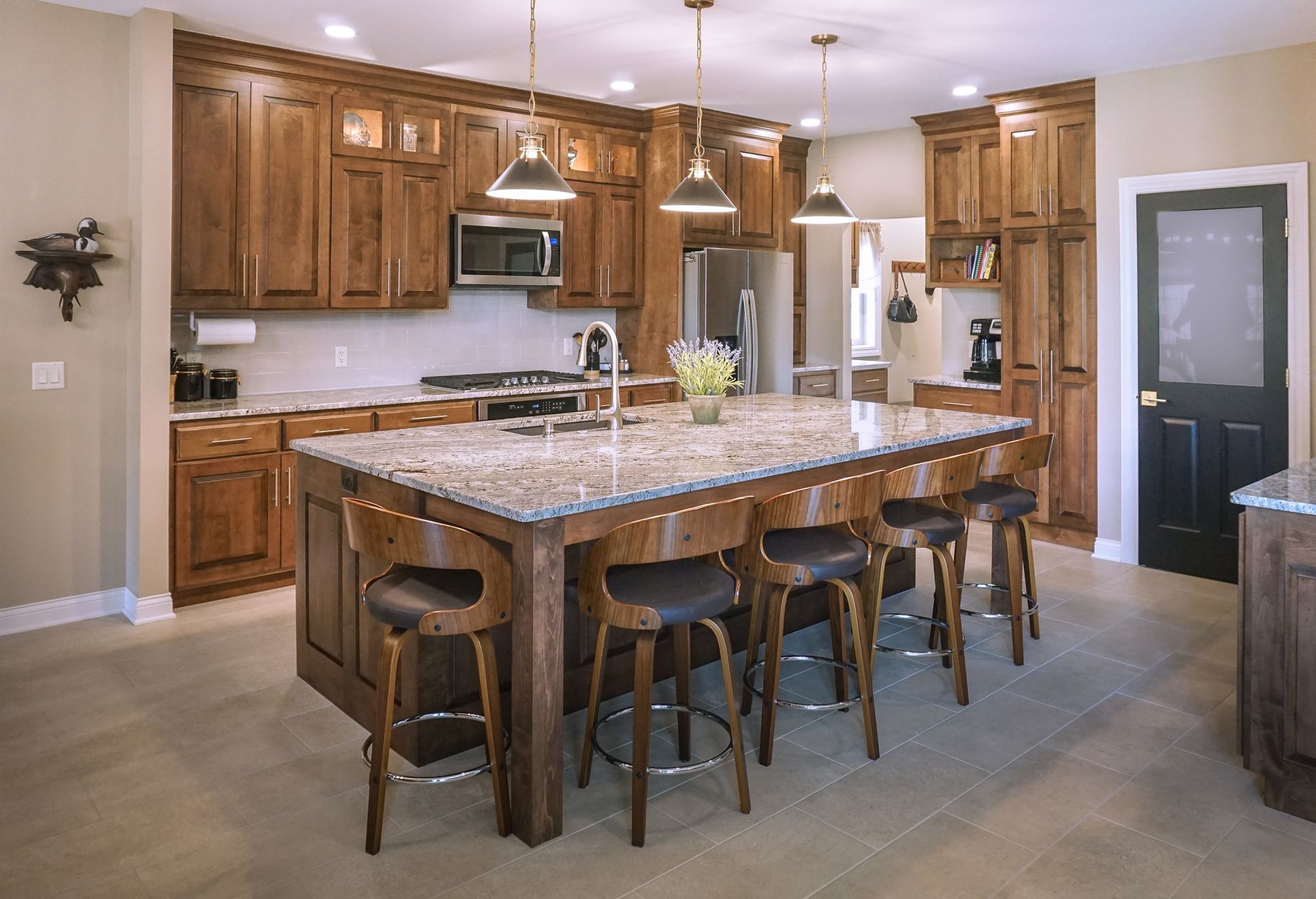 Custom, traditional stained kitchen cabinets and island, stainless appliances and unique pendant lights.