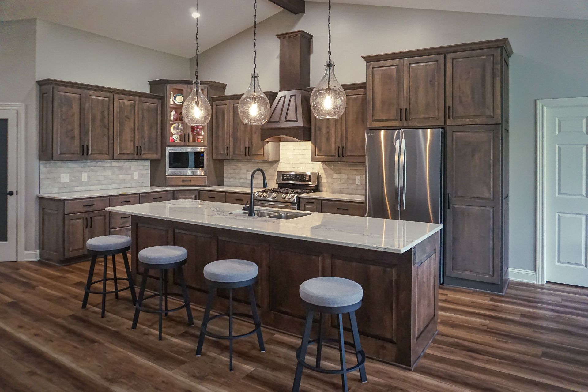 Custom dark stained wood kitchen cabinets and island with pendant lights.