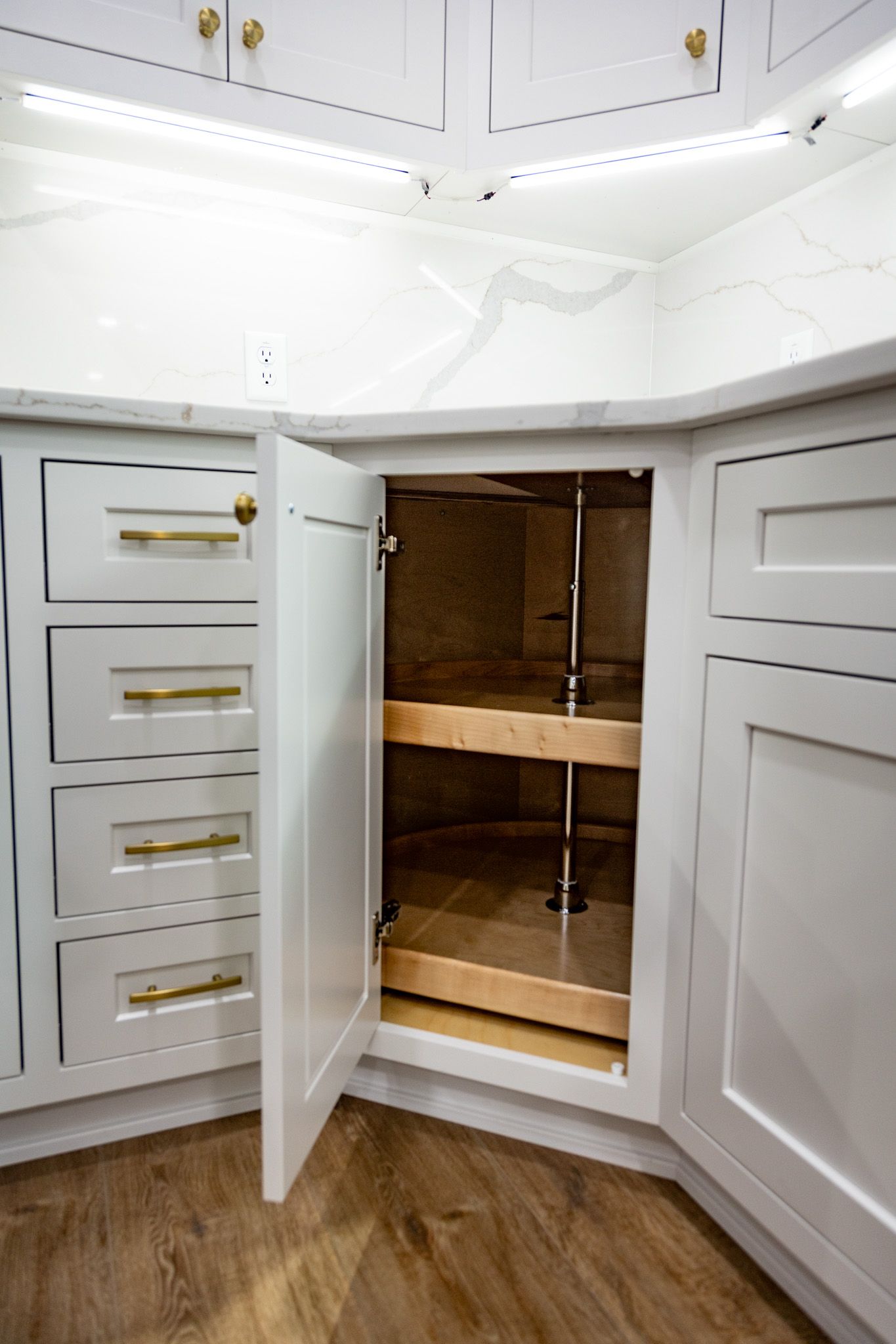 Custom white wood base kitchen cabinets with lazy susan corner storage solution.
