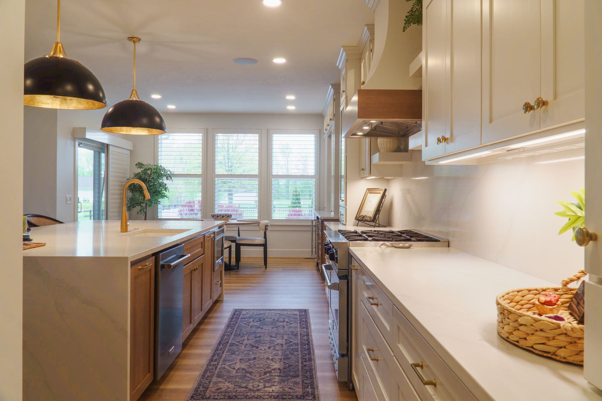 Custom, modern painted kitchen cabinets and stained wood  island with waterfall style quartz countertop and pendant lights.
