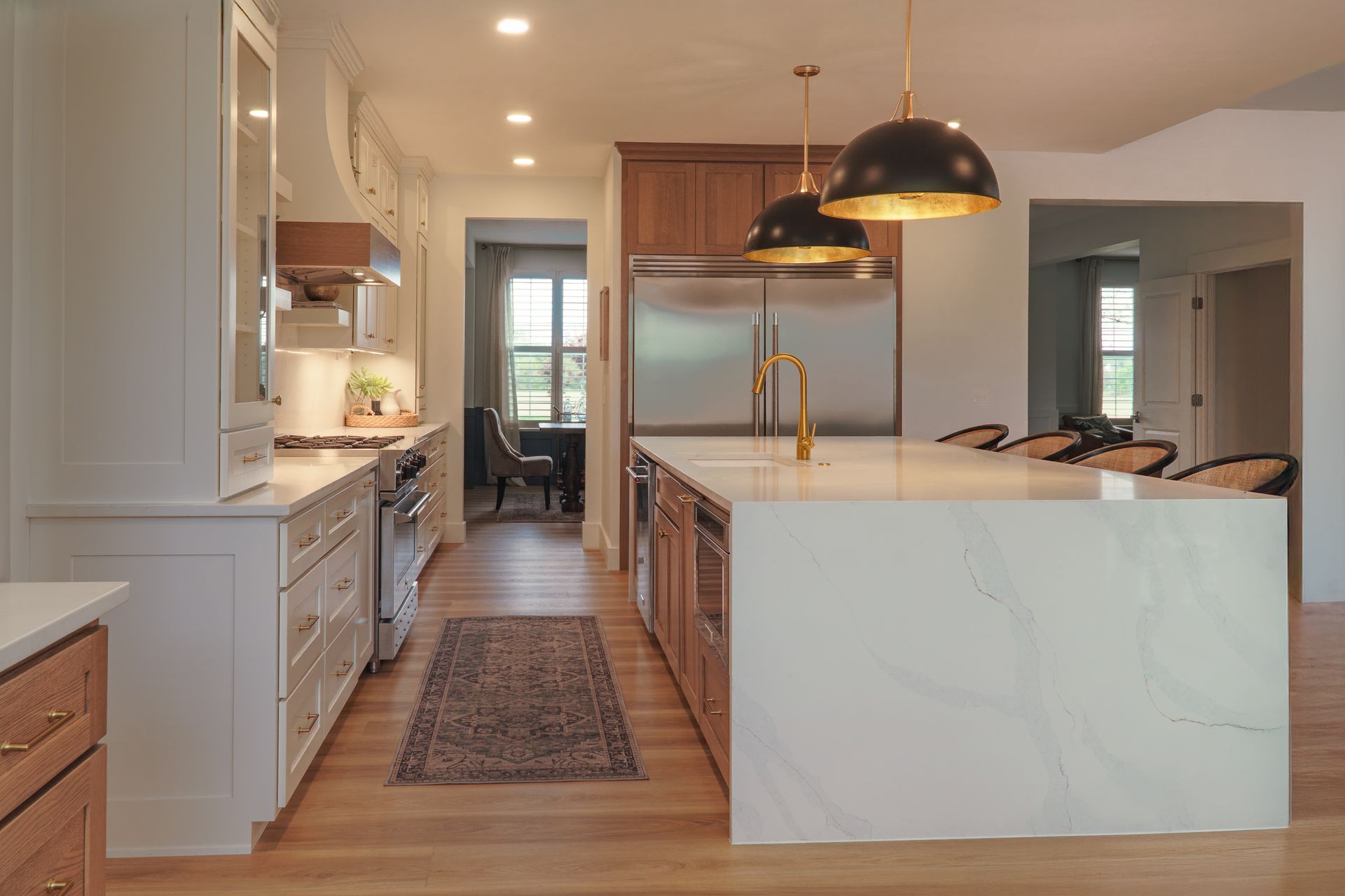 Custom, modern painted kitchen cabinets and stained wood  island with waterfall style quartz countertop and pendant lights.