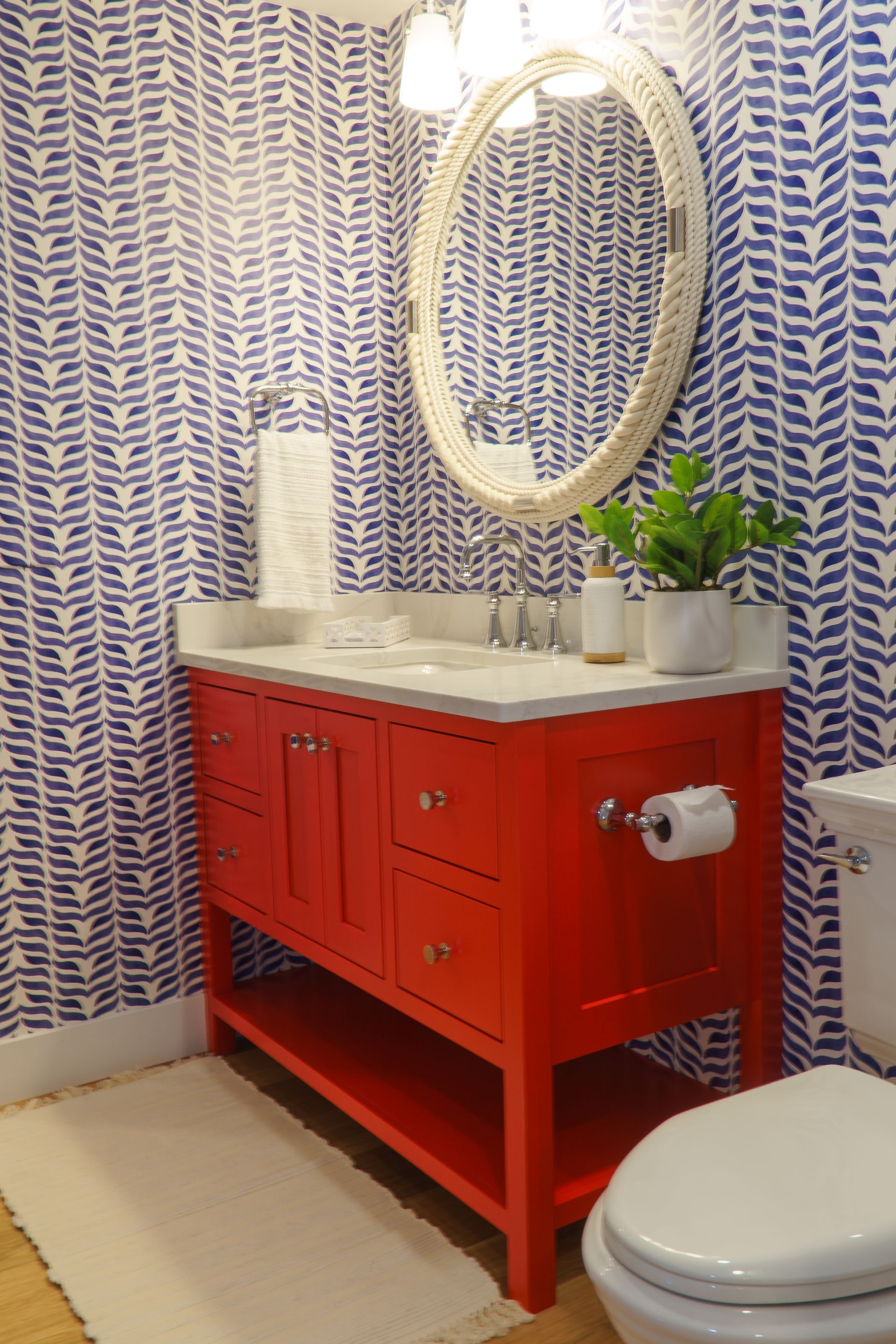Custom painted bright red bathroom vainity with oval mirror.