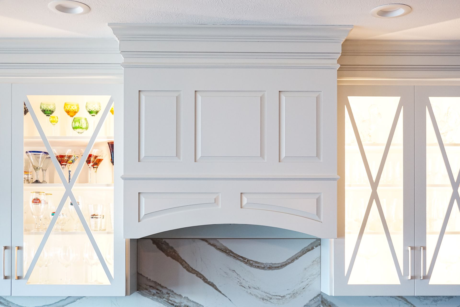 Custom white painted wood range hood with arched opening and raised panels.