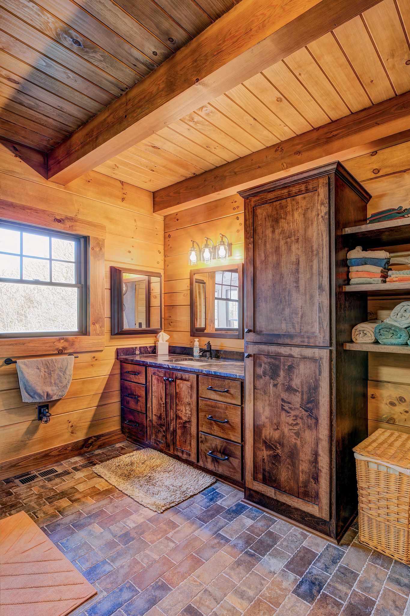 Custom dark stained wood bathroom vanity with linen closet in a log home.