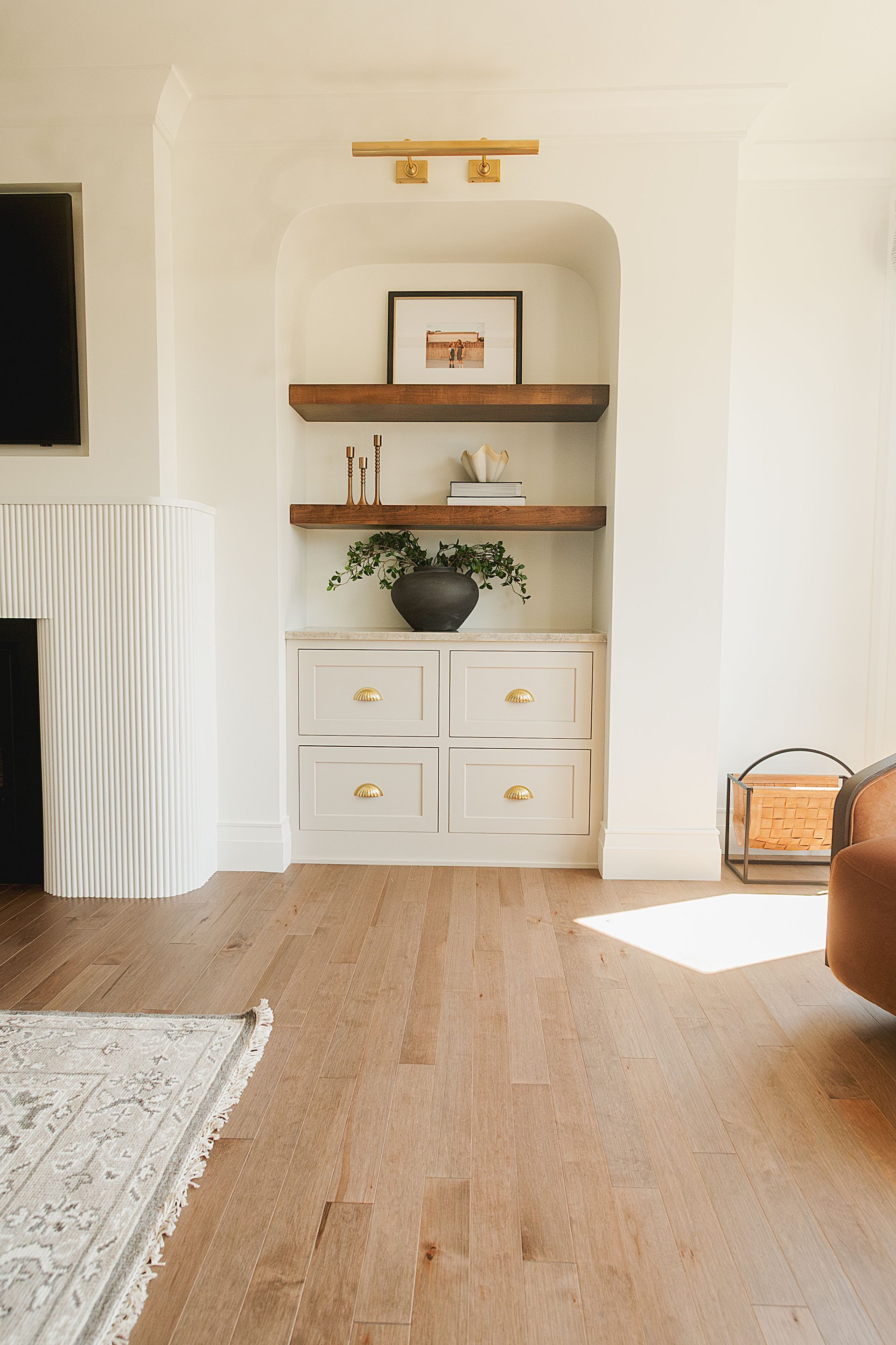 Custom white painted wood cabinet and stained floating shelves with arched opening.