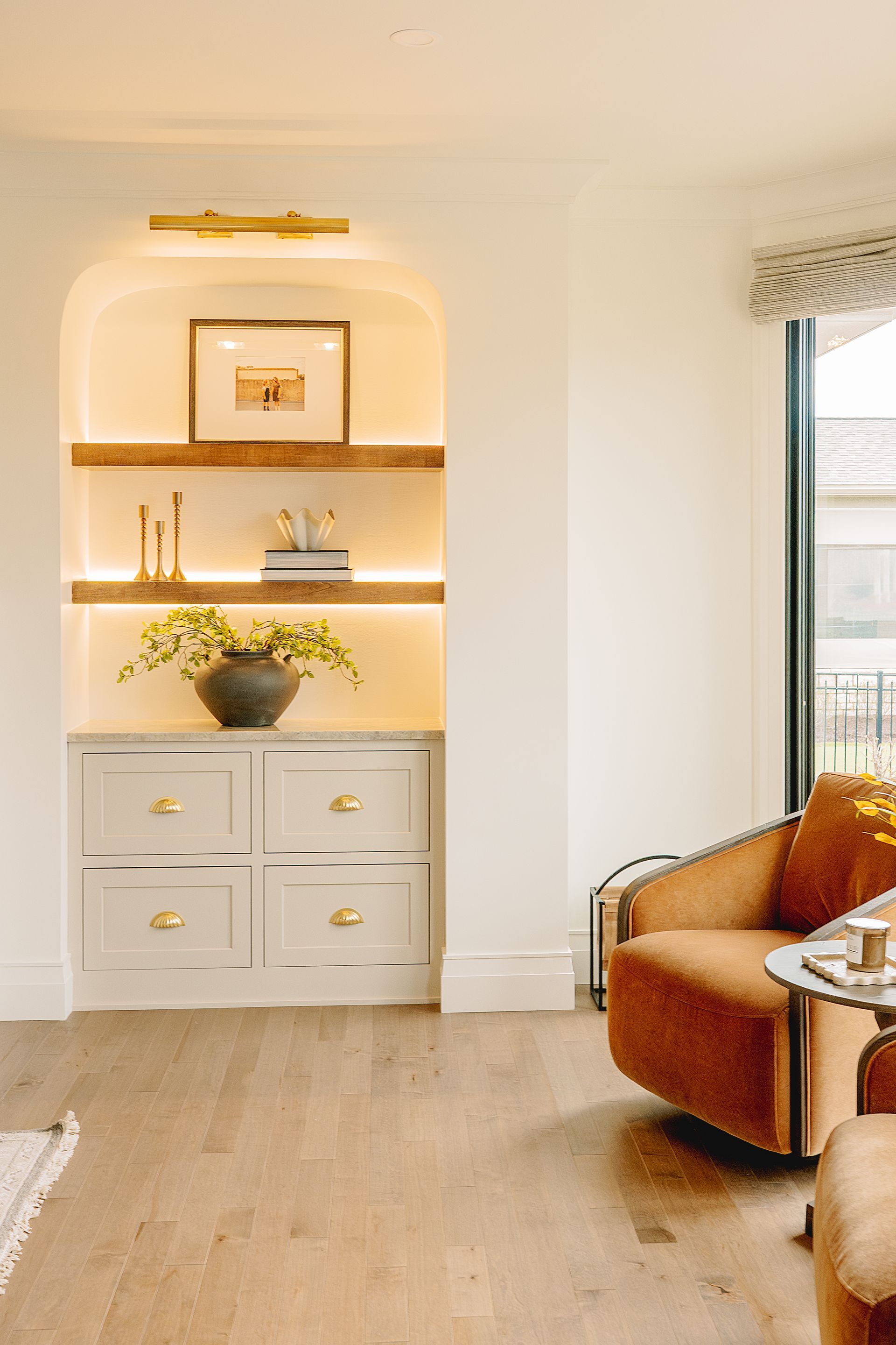 Custom white painted wood cabinet and stained floating shelves with arched opening.