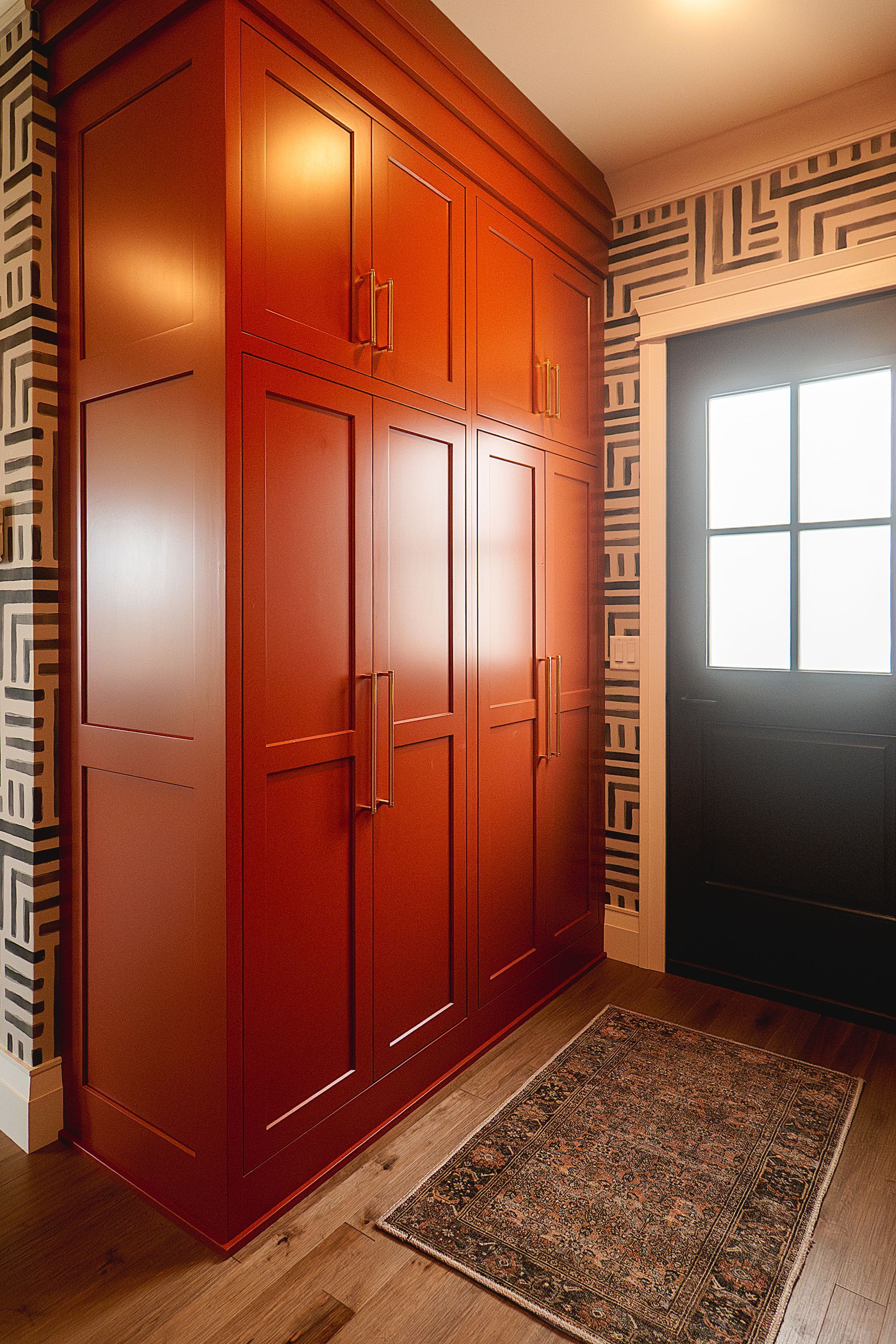 Custom red painted wood entry or mudroom coat closet and storage.