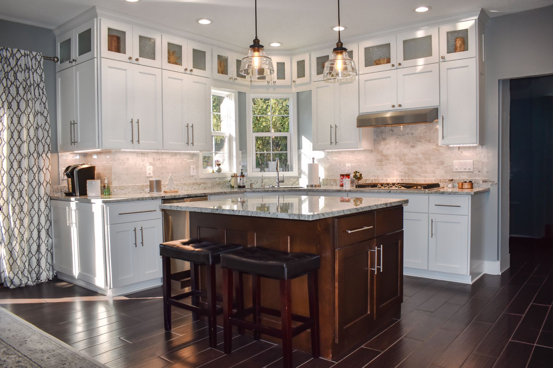 Custom white painted floor to ceiling kitchen cabinets with dark stained wood island.