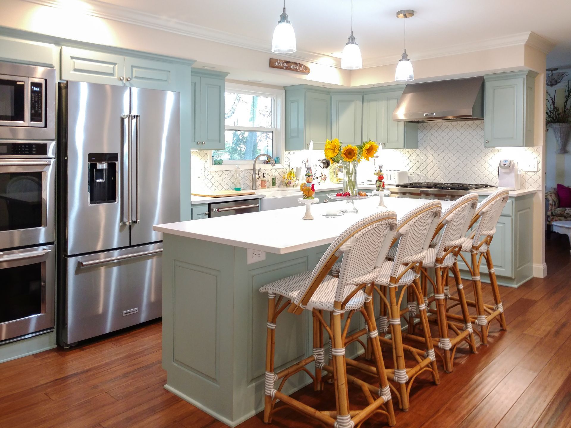 Custom dusty blue painted wood kitchen cabinets and island with built in stainless appliances.