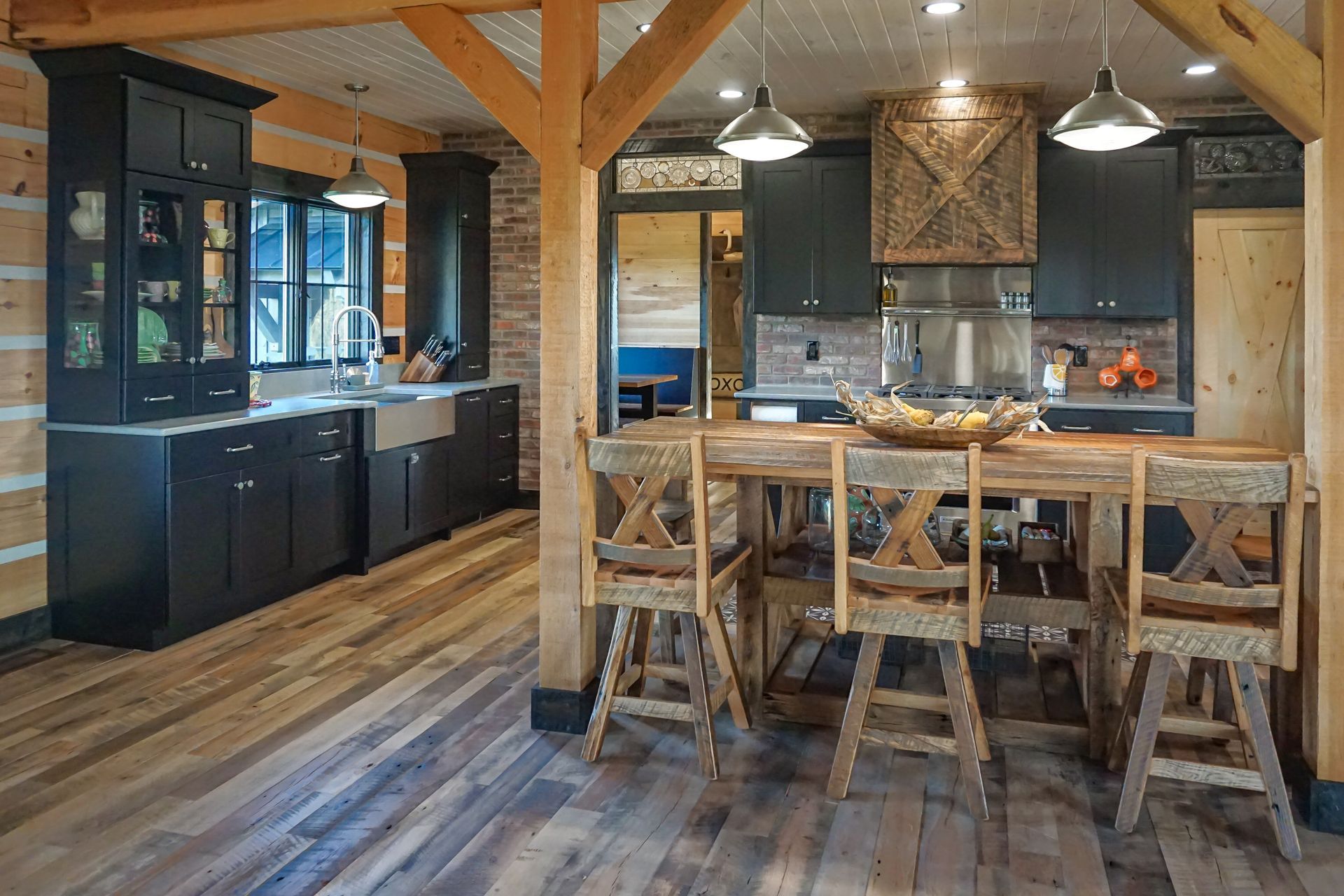 Custom black painted wood kitchen with farmhouse sink and rustic rough sawn wood island.