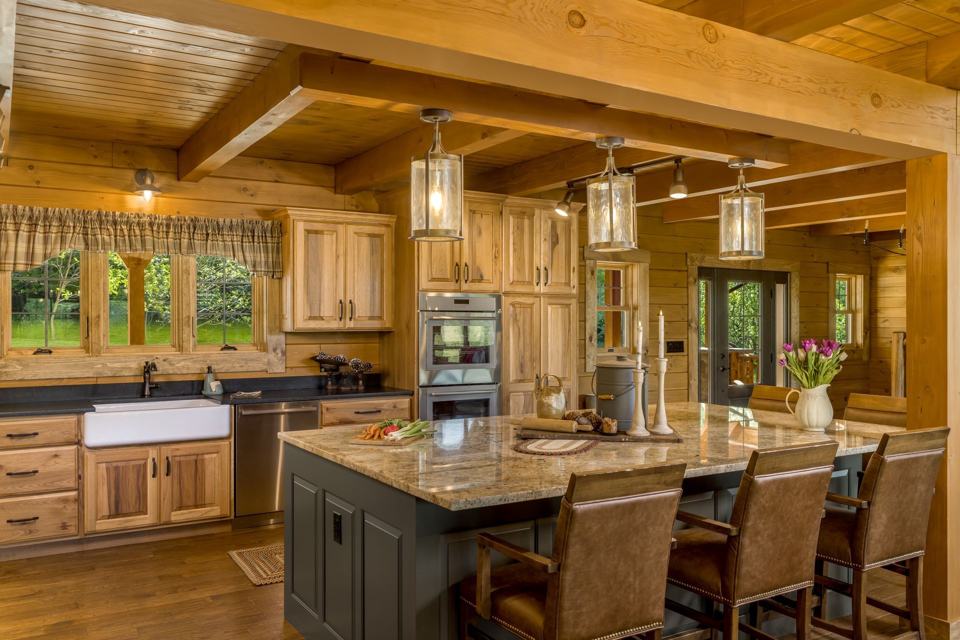 Custom stained hickory kitchen cabinets and farmhouse sink in a log home for a warm look.