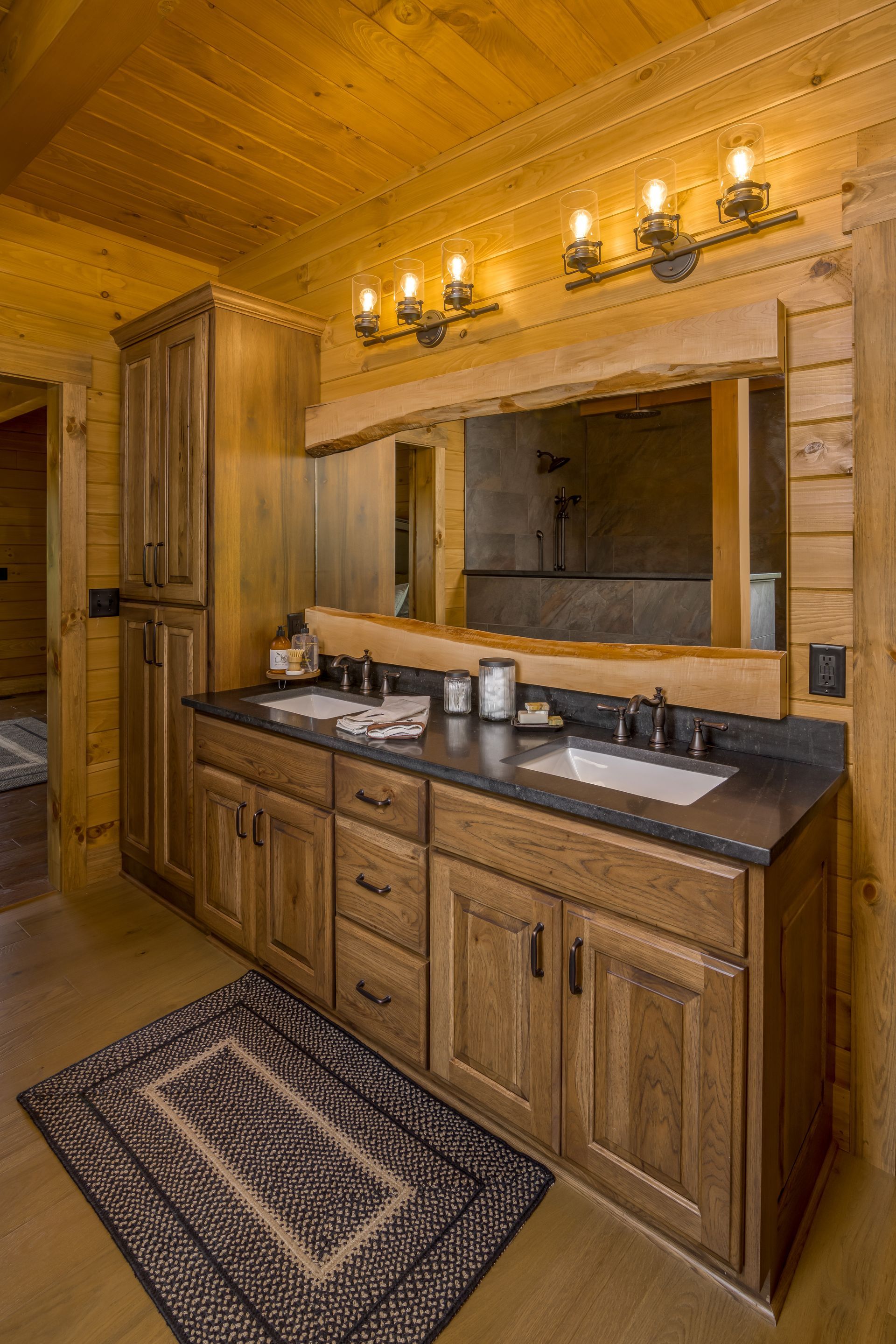 Custom stained hickory bathroom vanity and linen closet in a log home for a warm look.