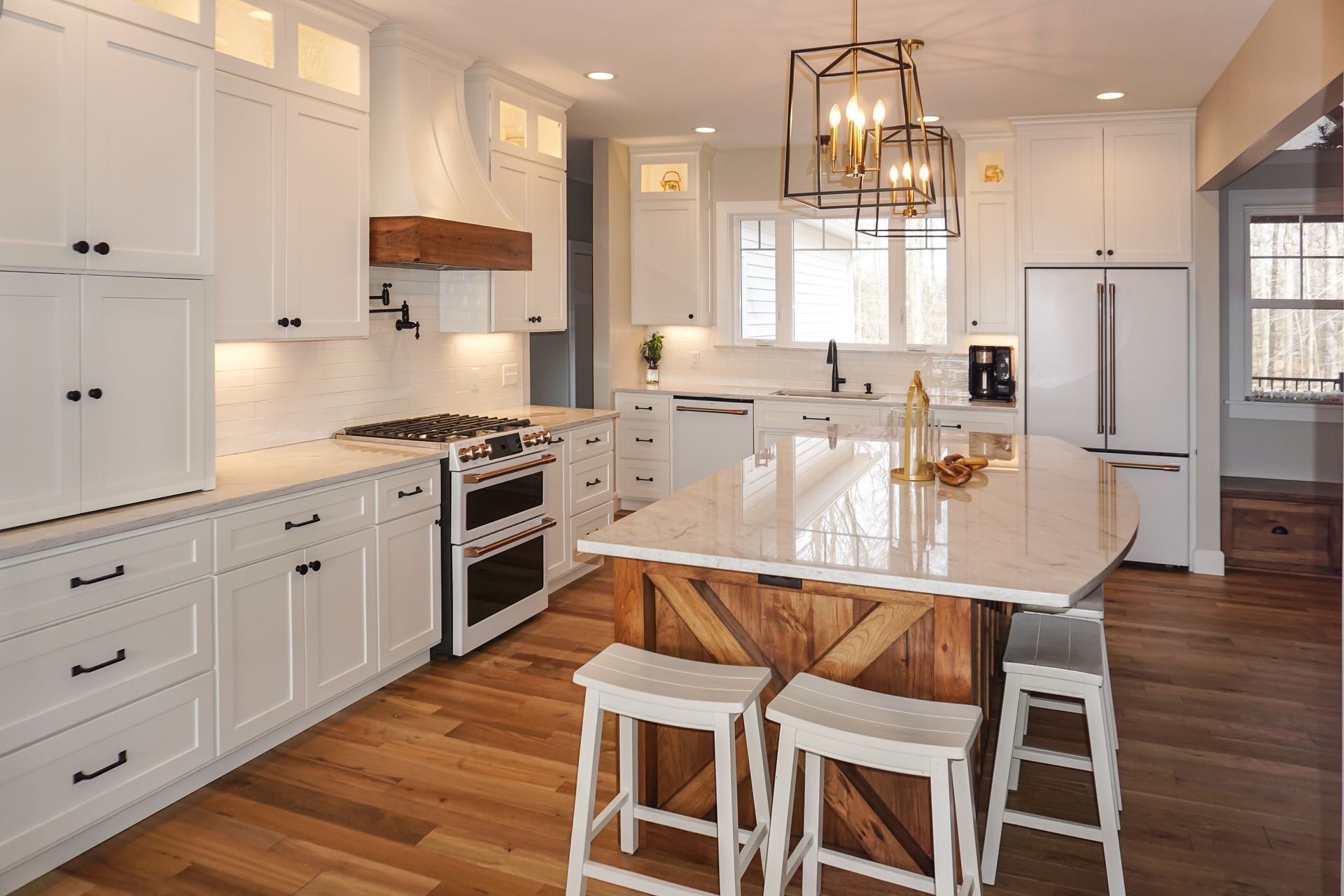 Custom, modern white painted kitchen cabinets and stained wood island with curved quartz countertop and white appliances.
