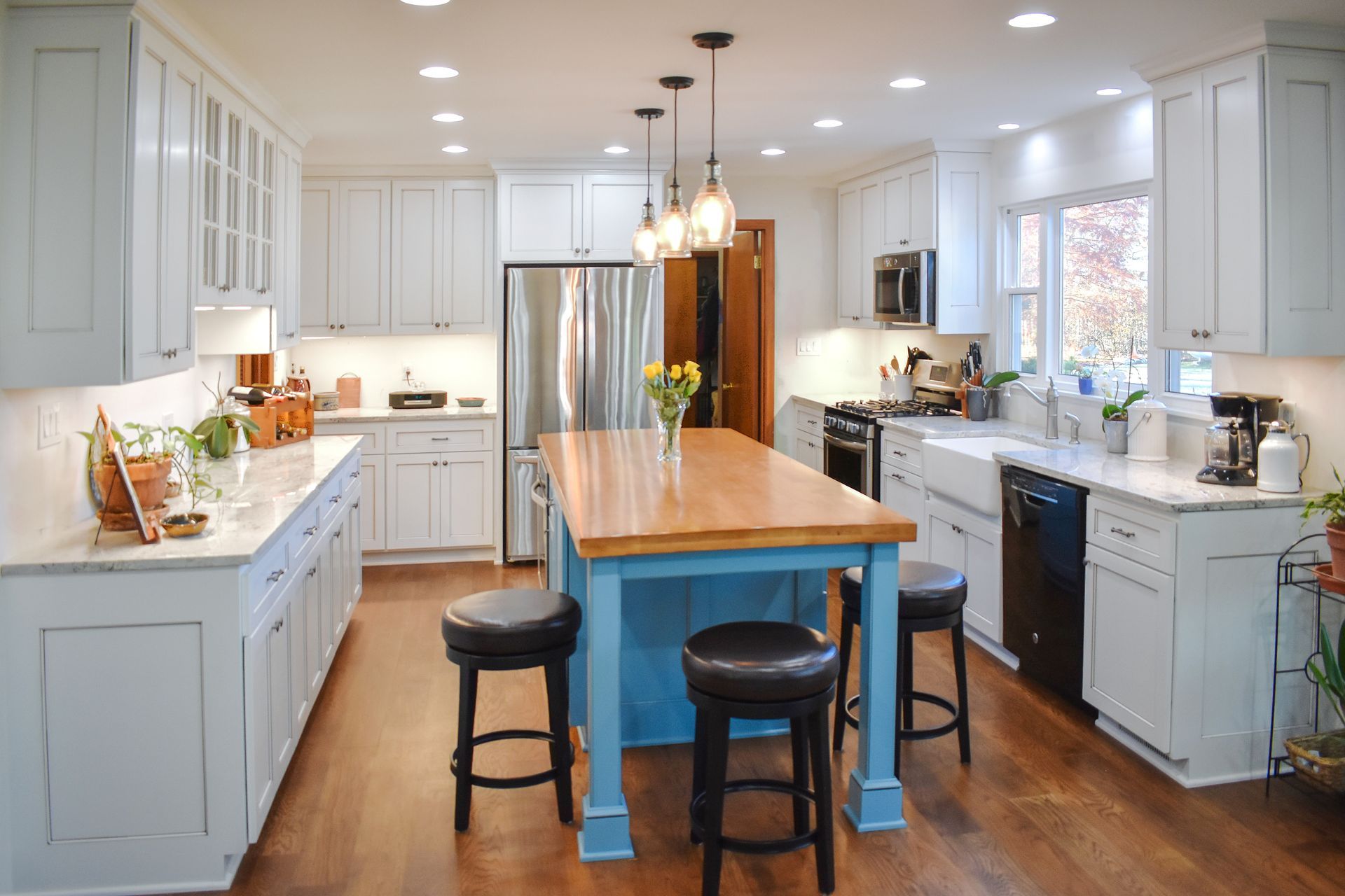 Custom, modern white painted kitchen cabinets and blue painted wood island and pendant lights.