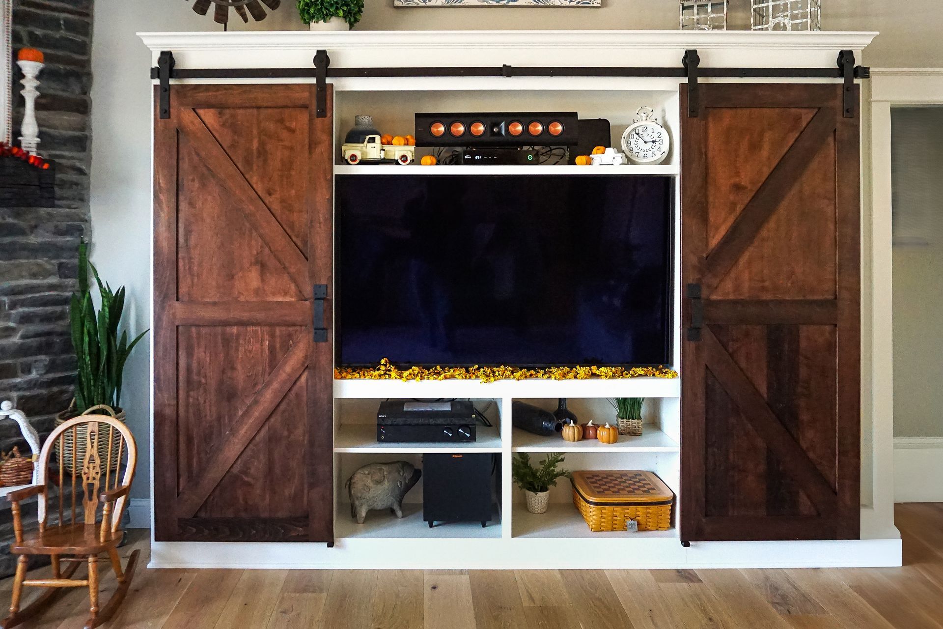 Custom white painted wood entertainment center with sliding wood barn doors open.