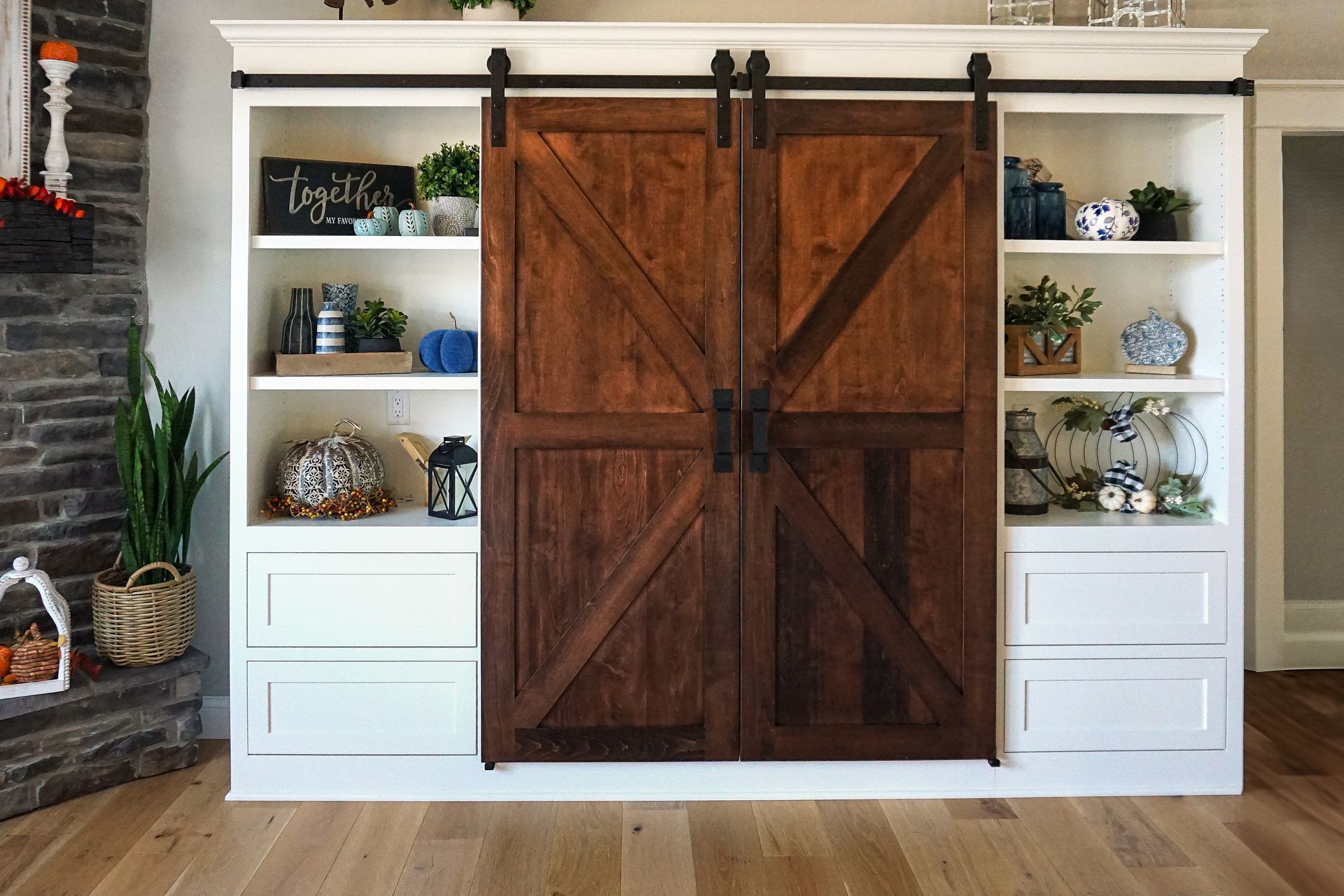 Custom white painted wood entertainment center with sliding wood barn doors closed.
