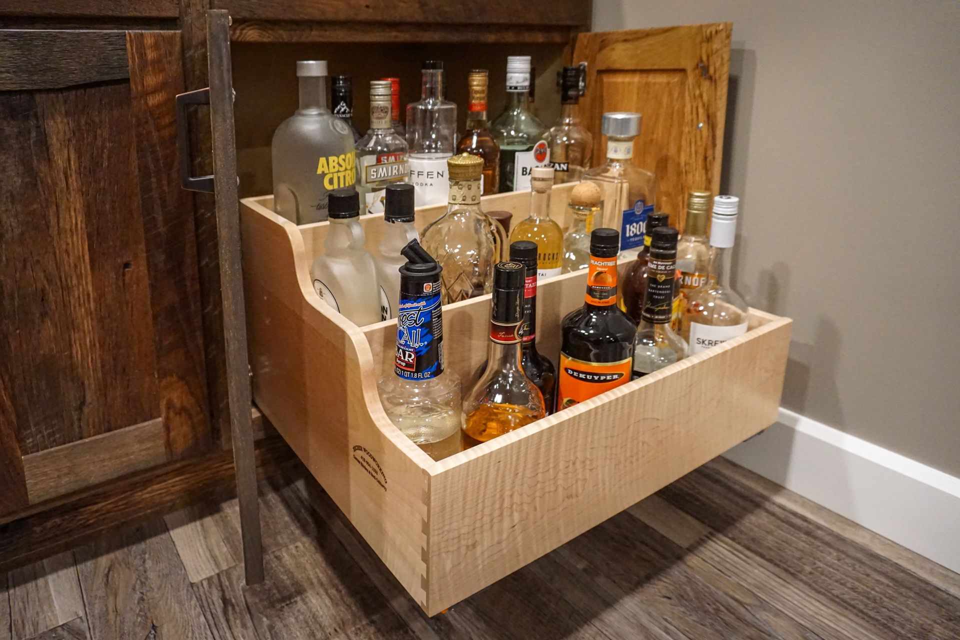 Custom stained wood cabinet with pullout drawer for wine and wiskey storage.