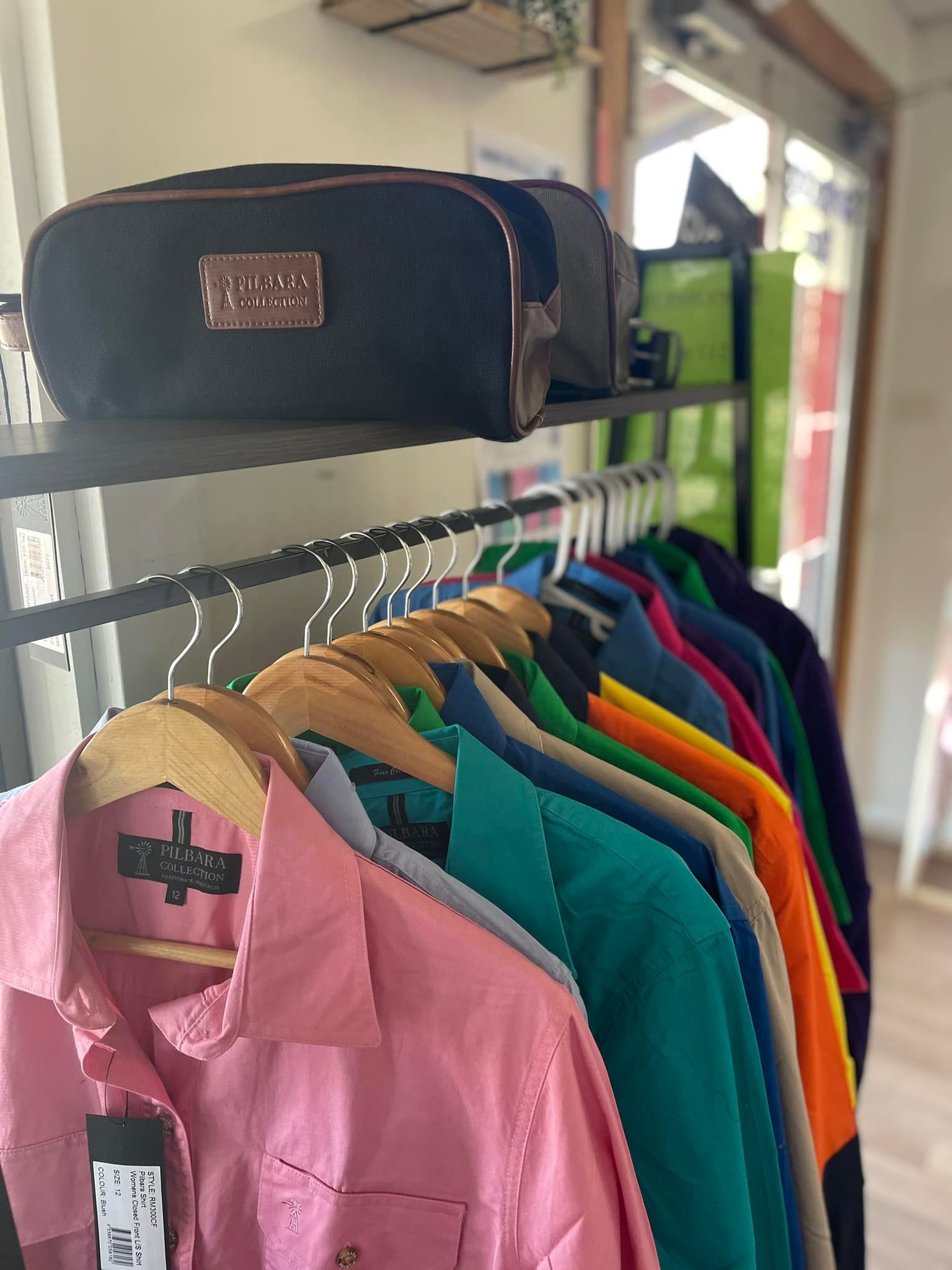A row of shirts are hanging on a rack in a store.