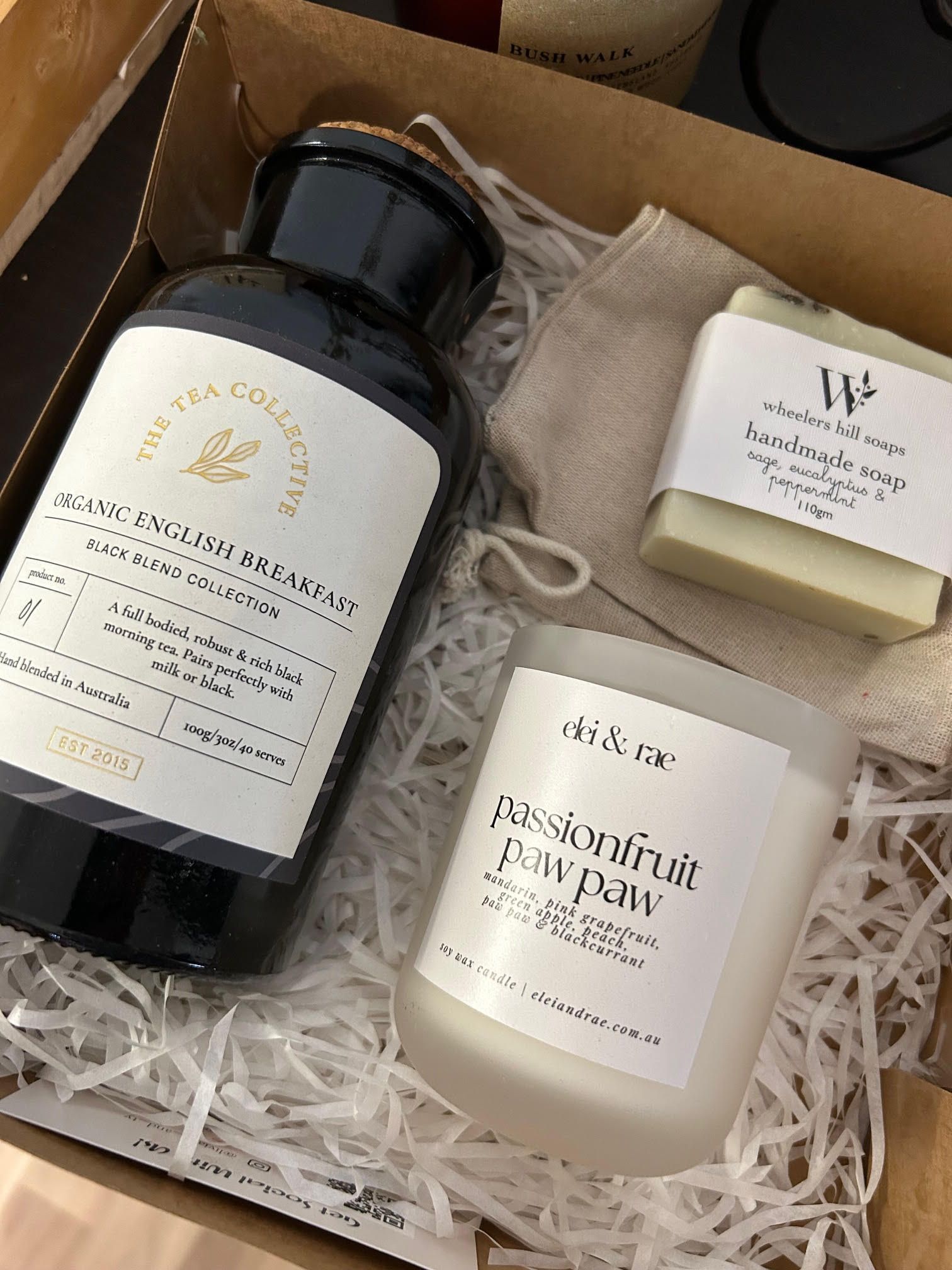 A box filled with a bottle of soap , a candle , and a soap bar.