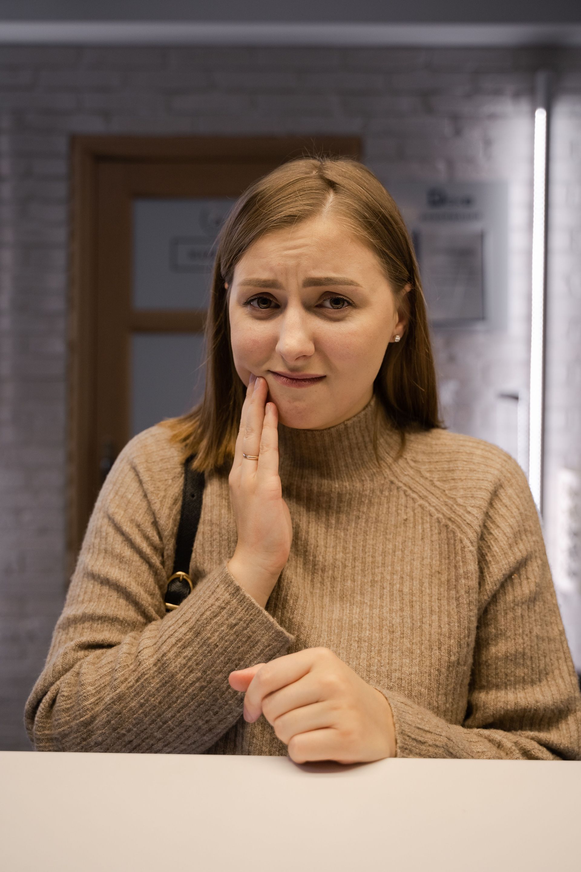 Dentist examining a woman with cheek pain in a clinic, gloved hand touching her face