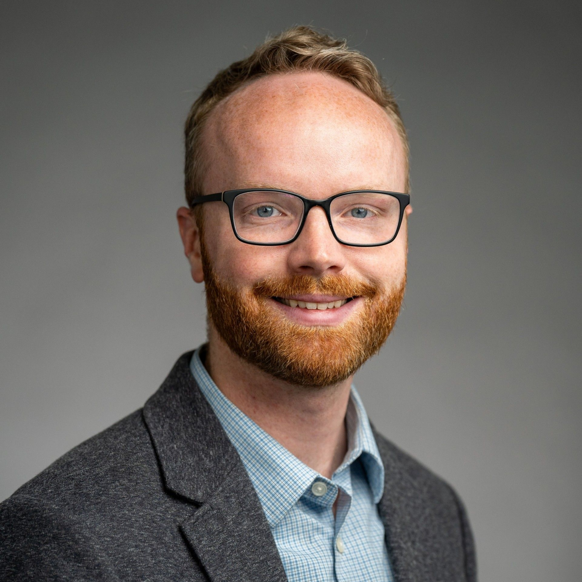 A bald man in a suit and tie is smiling for the camera.