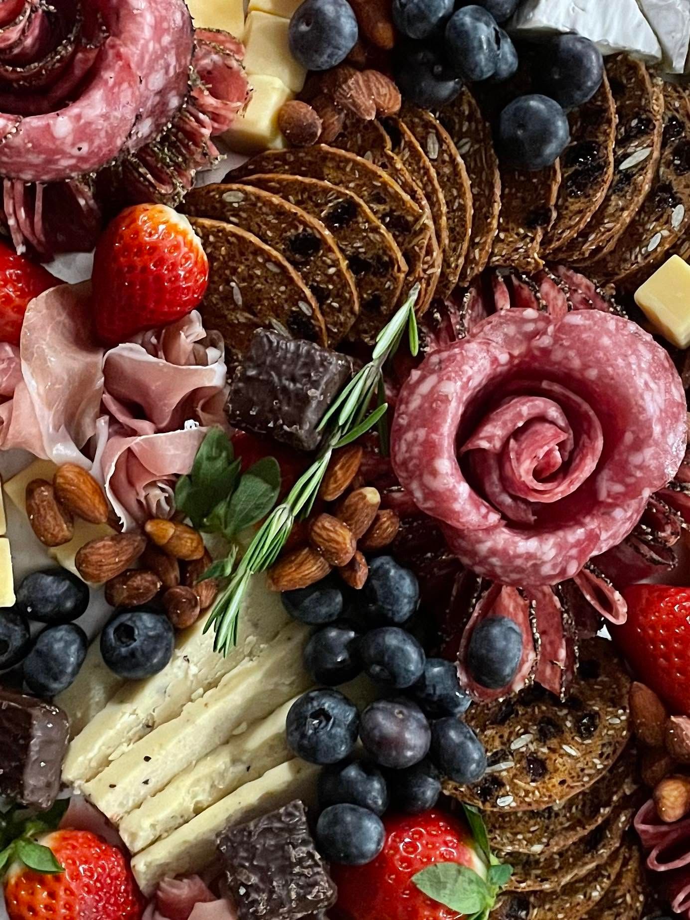 Charcuterie board with cured meats, cheeses, grapes, strawberries, blueberries, and crackers arranged decoratively