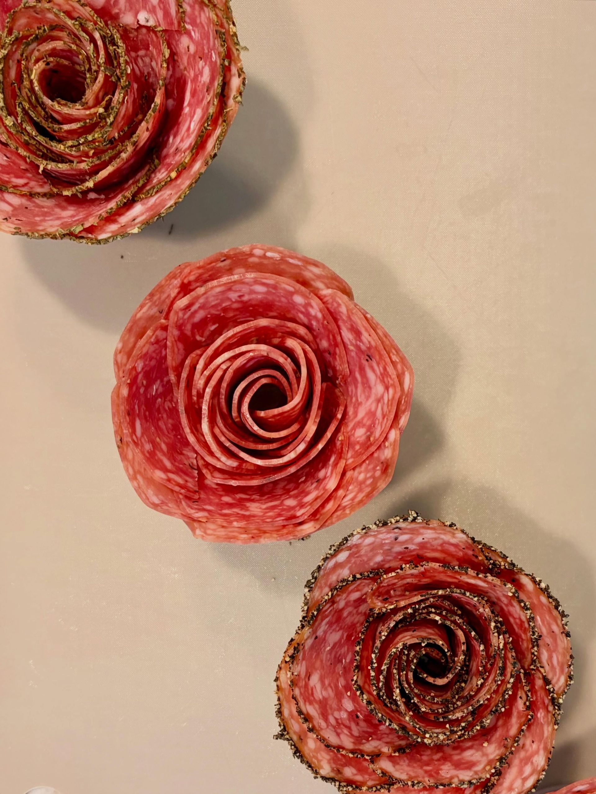Three pink-red spiral flower decorations on a light beige background.