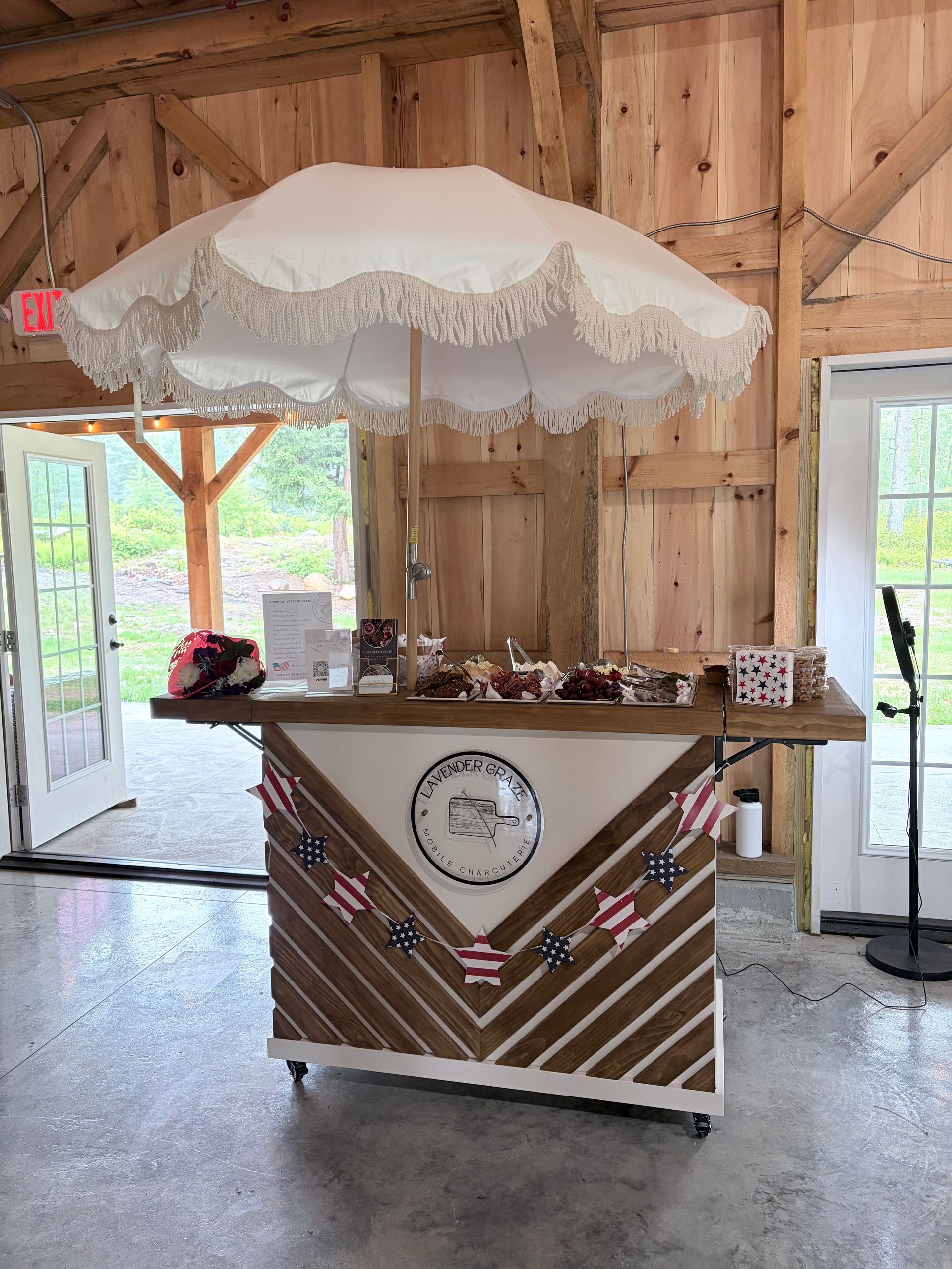 Rustic barn stall with a lace-trimmed umbrella over a decorated wooden cart stand