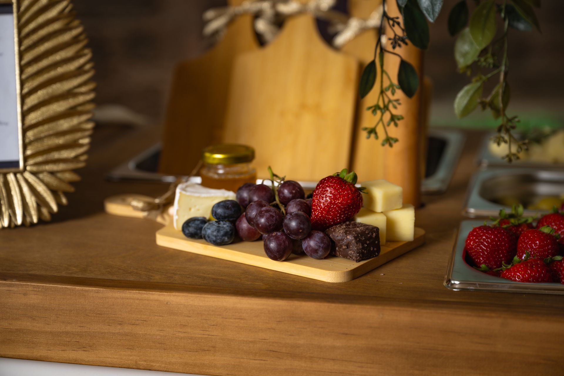 Assorted fresh berries on wooden trays on a table, with strawberries and blueberries in a cozy kitchen setting