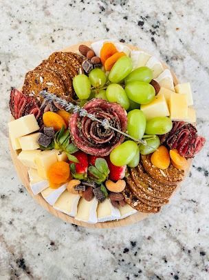 Charcuterie board with grapes, cheese cubes, crackers, dried fruit, and nuts on a marble countertop