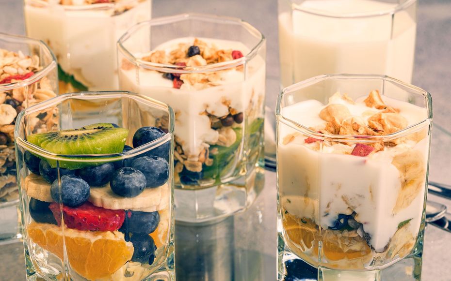 Assorted layered fruit and yogurt parfaits in glass cups on a table