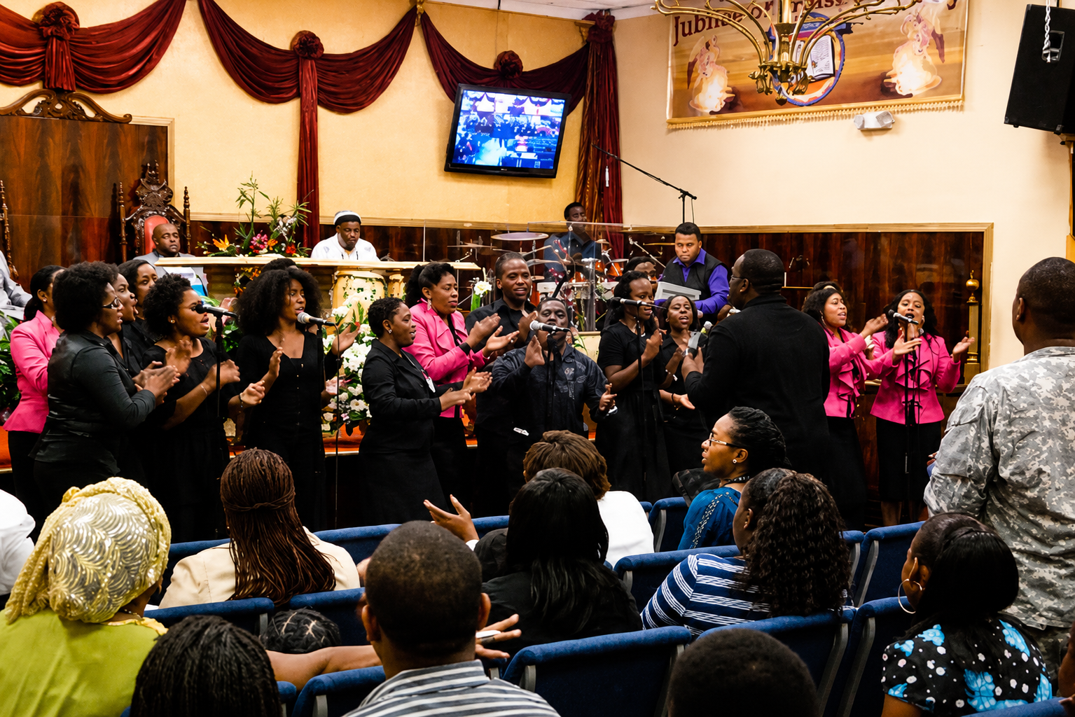 Choir performing in a decorated hall while an audience watches and claps