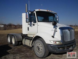 A white semi truck is parked in a dirt field.