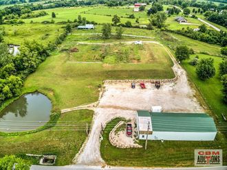 An aerial view of a farm with a building and a pond