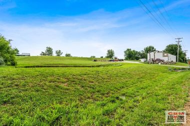 A large lush green field with a house in the background.