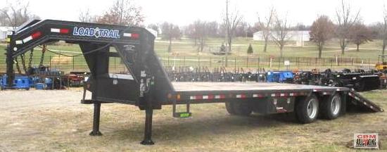 A flatbed trailer with a crane attached to it is parked in a field.