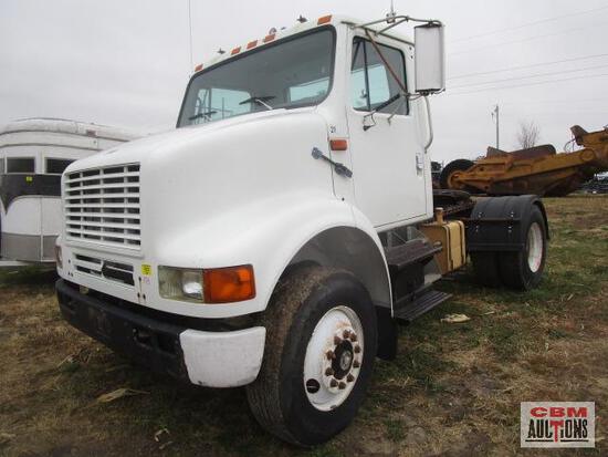A white semi truck is parked in a field.