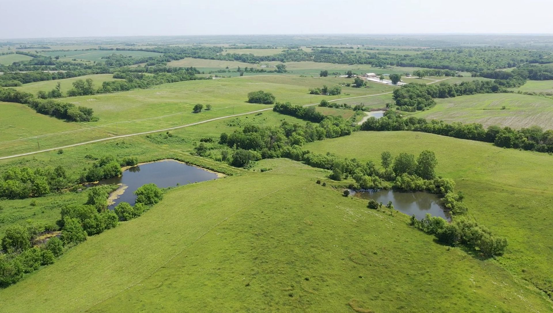 An aerial view of a lush green field with a small pond in the middle.
