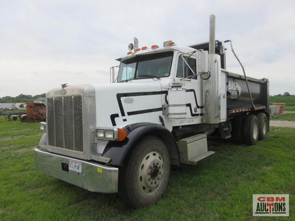 A white dump truck is parked in a grassy field.