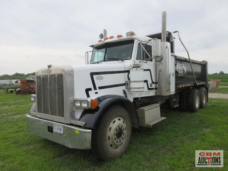 A white dump truck is parked in a grassy field.
