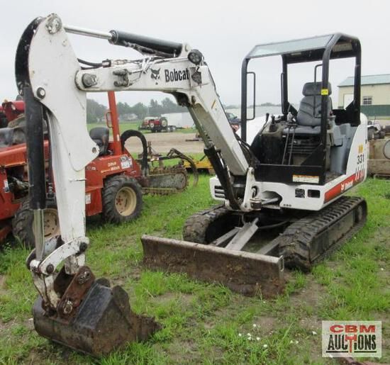 A bobcat excavator is parked in a grassy field