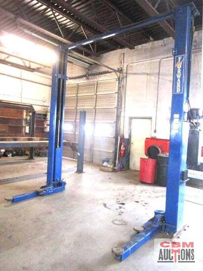 A blue car lift in a garage with a red truck in the background