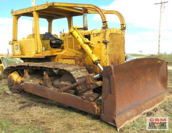 An old yellow bulldozer is parked in a field