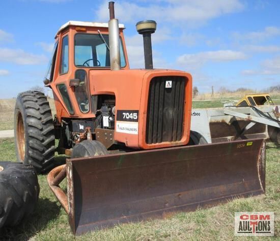 An orange tractor with a bulldozer attached to it