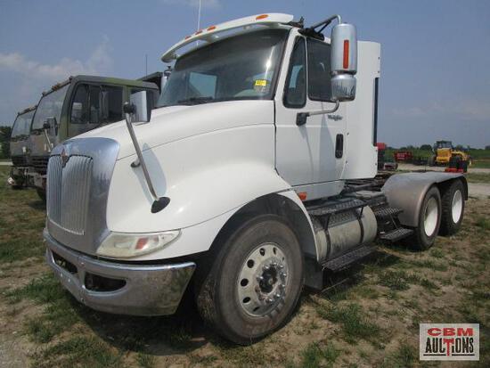 A white semi truck is parked in a grassy field.