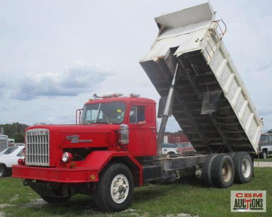 A red dump truck is parked in front of a sign that says gbm auctions