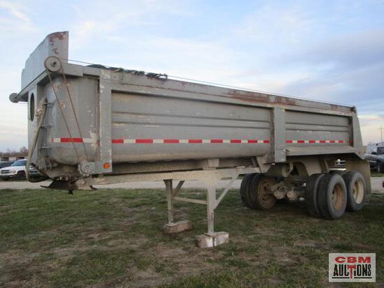A dump truck is parked in a grassy field.